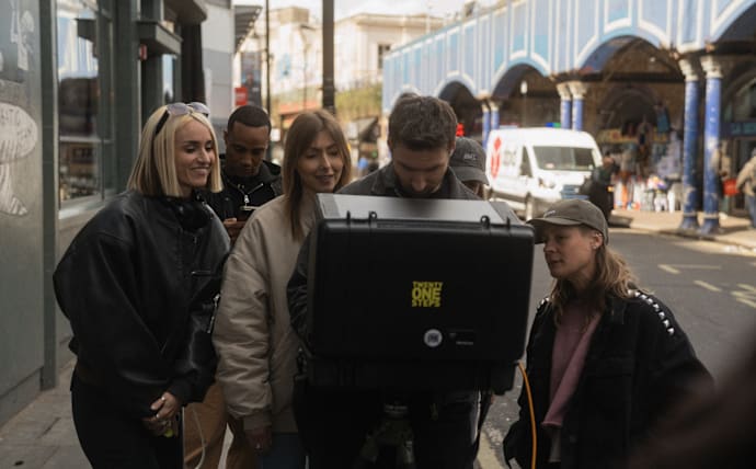 Behind-the-scenes campaign production with crew members reviewing footage on a monitor during a BUFFALO photoshoot in an urban street setting.