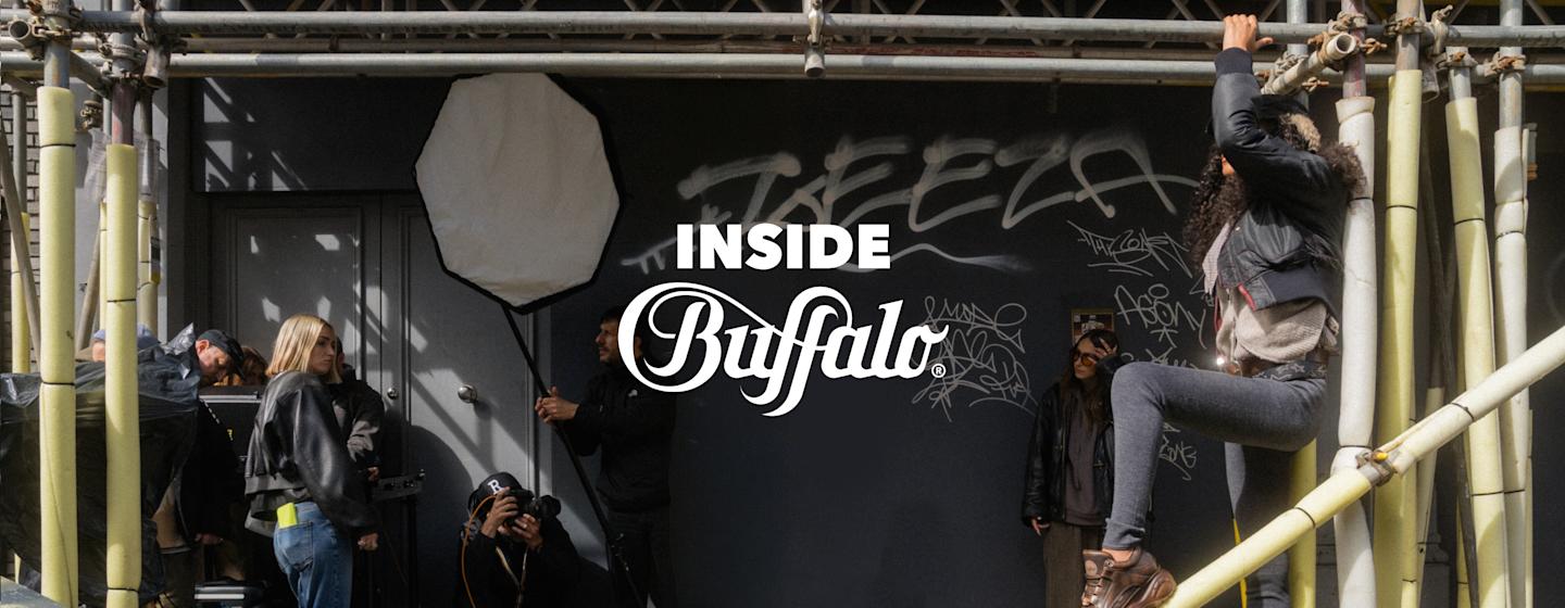 Behind-the-scenes photoshoot at an urban location with scaffolding, photography equipment and crew members preparing a BUFFALO campaign shoot.