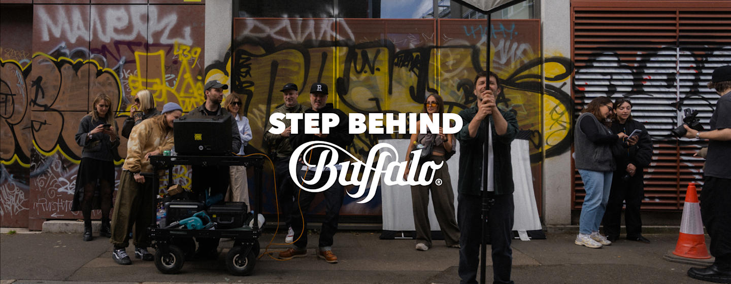 Behind-tBehind-the-scenes moments from a BUFFALO campaign shoot, with the production crew and creative team gathered on an urban street sethe-scenes photoshoot at an urban location with scaffolding, photography equipment and crew members preparing a BUFFALO campaign shoot.