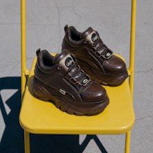 Brown chunky sneakers on a yellow chair.