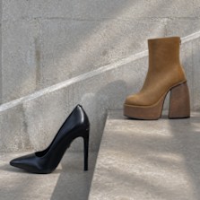 Black stiletto pump and tan platform ankle boot on concrete steps.