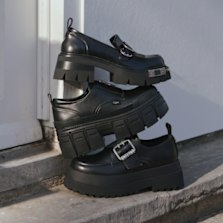 Black chunky loafers with oversized platform soles stacked on steps.