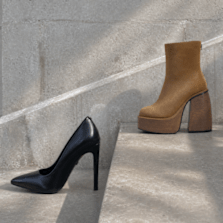Black stiletto pump and tan platform ankle boot on concrete steps.