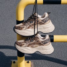 Leopard print chunky sneakers hanging on a yellow railing.