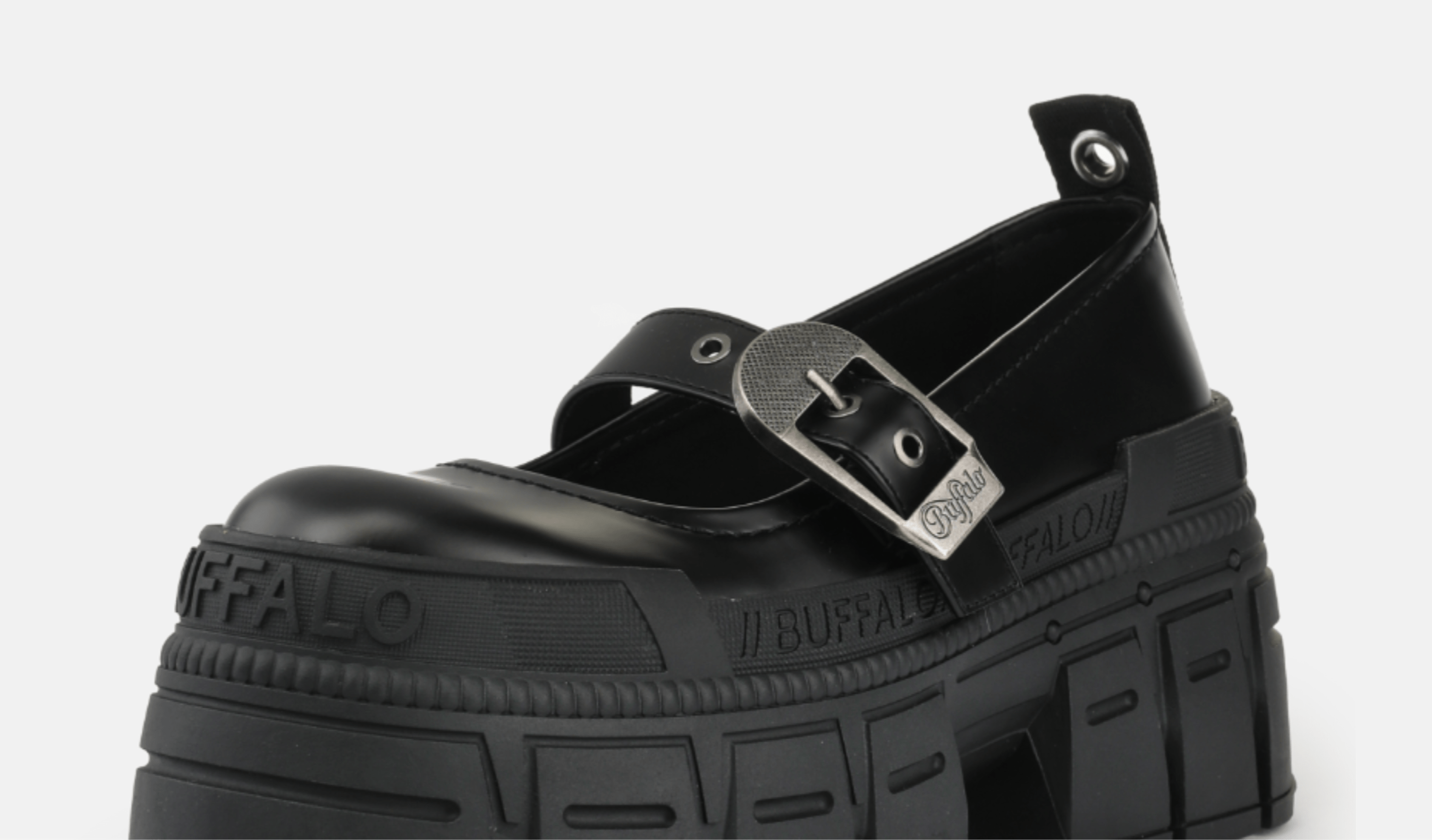 Close-up of a black platform Mary Jane shoe with buckle strap and chunky sole on a light background